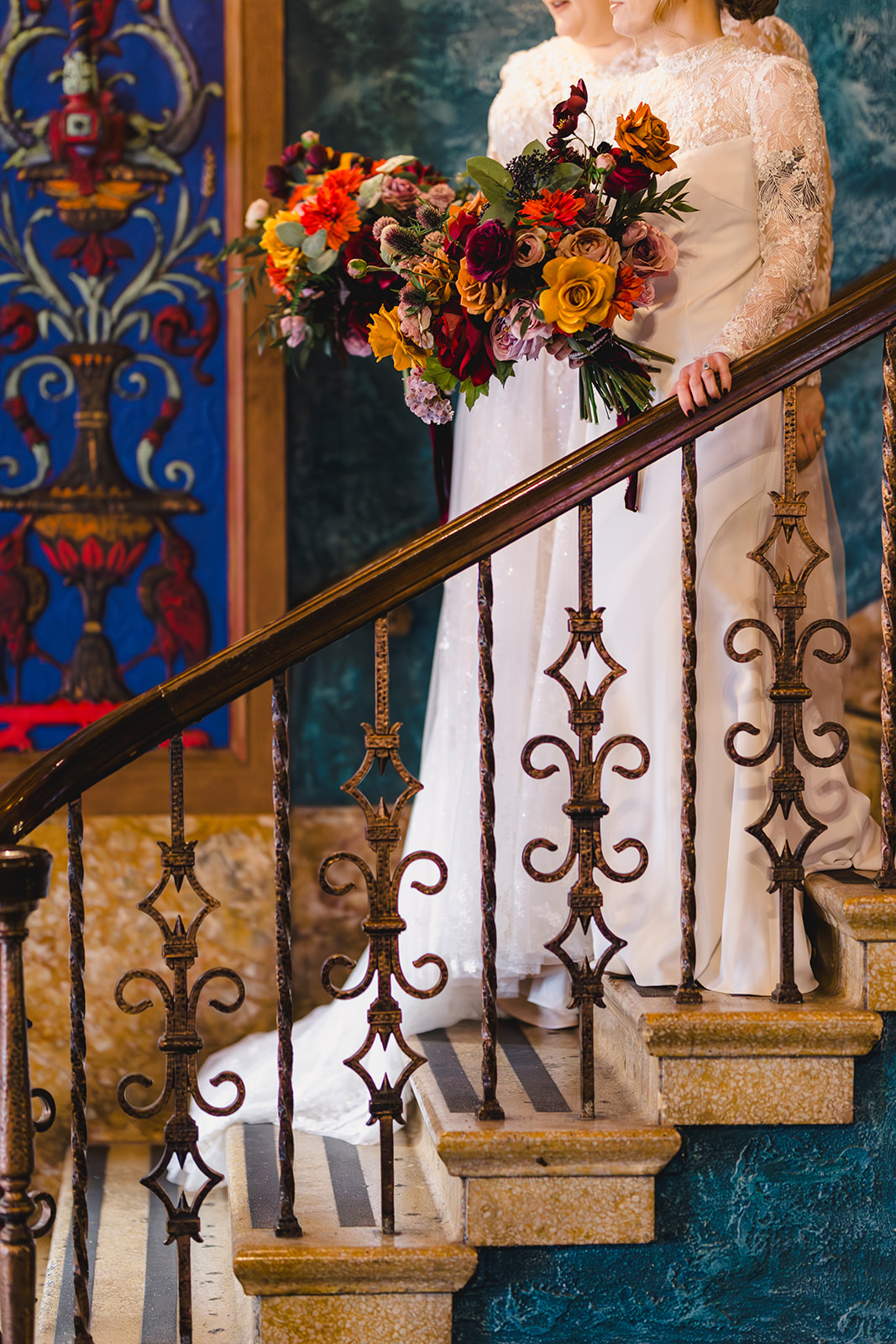 two brides standing on the staircase together inside of the uptown theater in kansas city 