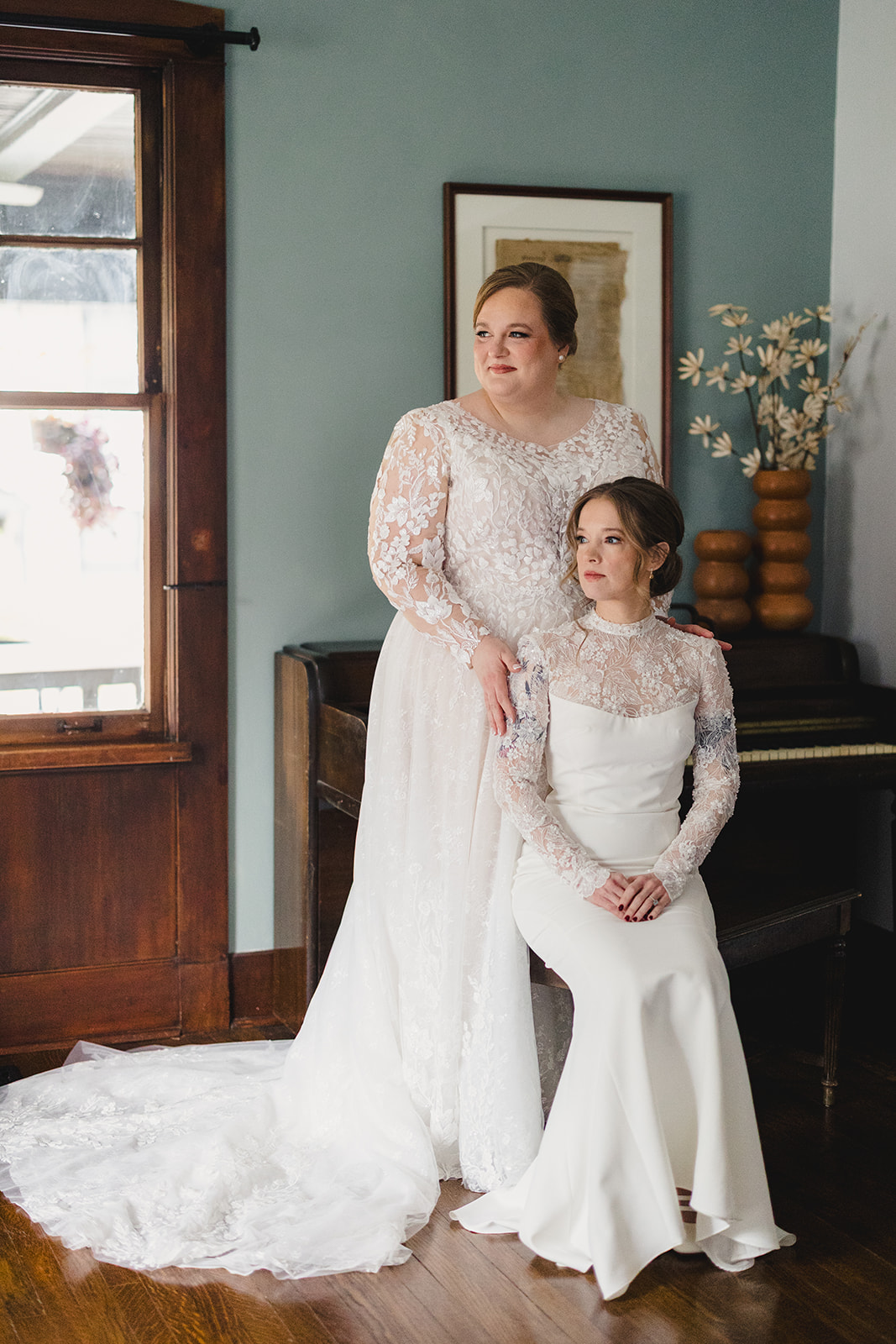 two brides taking wedding portraits together one bride is sitting the other is standing behind her 