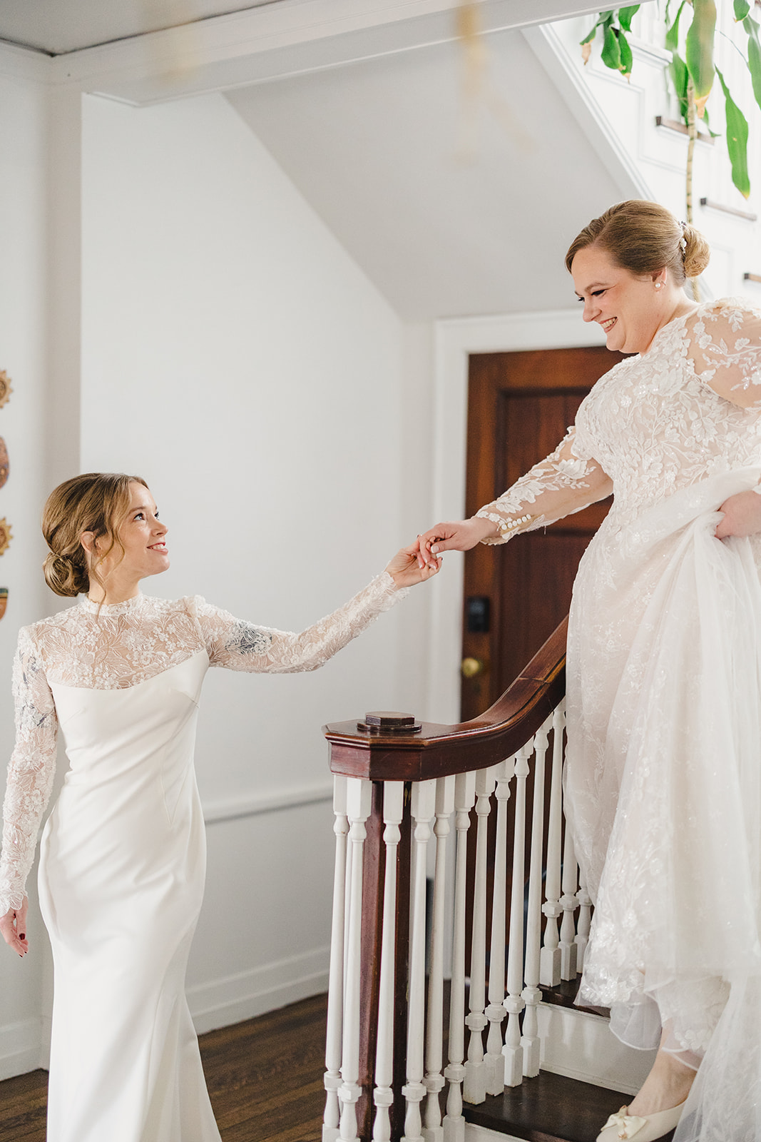 two brides walking down the stairs to greet each other they are holding hands and smiling at each other 