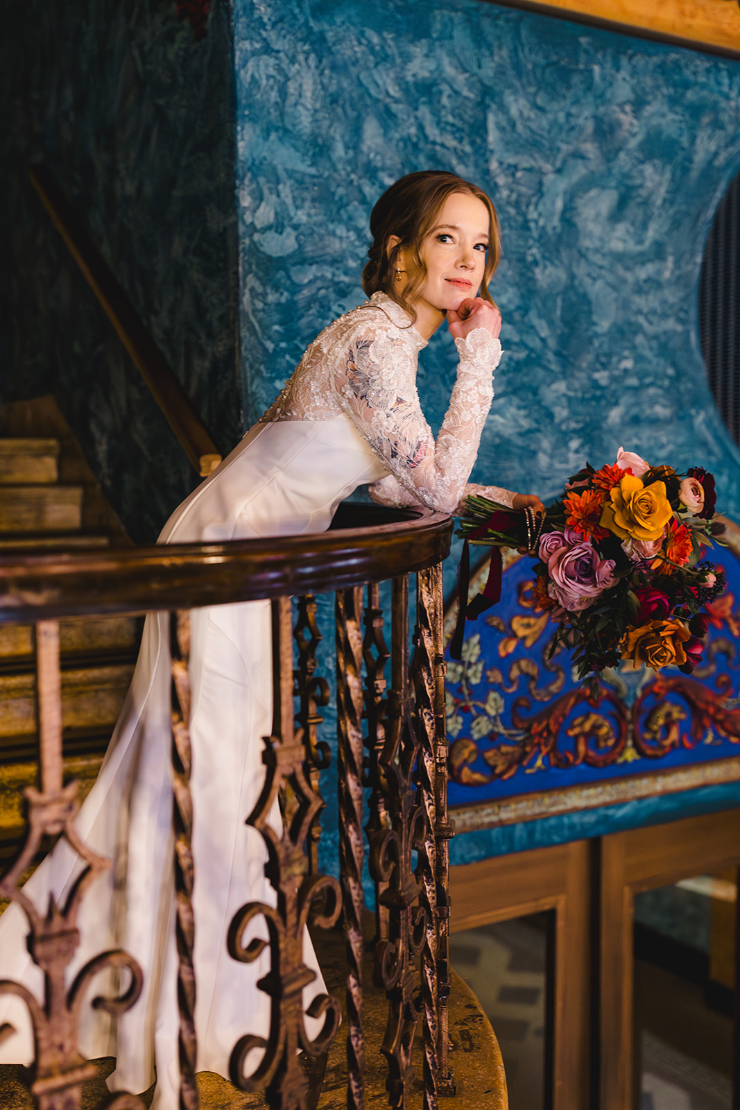 a bride taking a wedding portrait leaning against a staircase role in the uptown theater in kansas city 