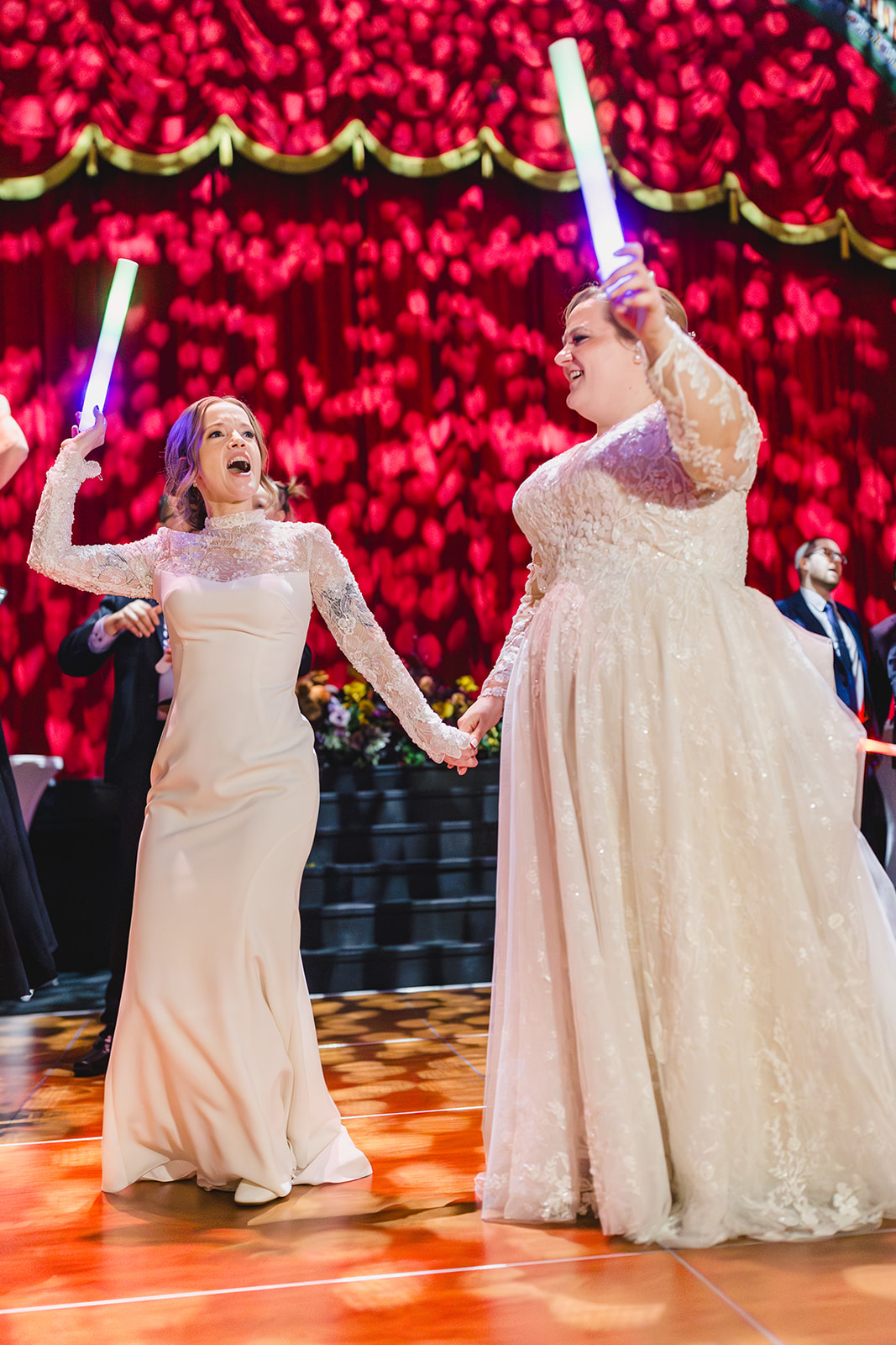 two brides dancing at their wedding reception inside of the uptown theater in kansas city dancing with glow sticks 