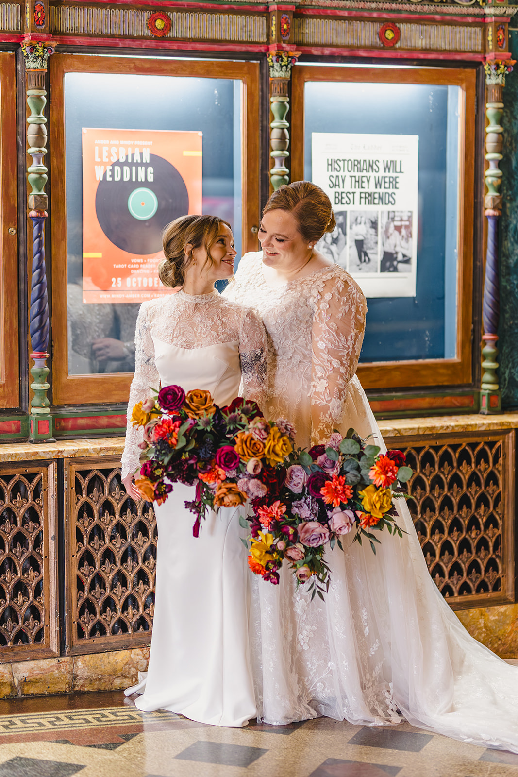 two brides taking wedding photos together inside of the uptown theater in kansas city 