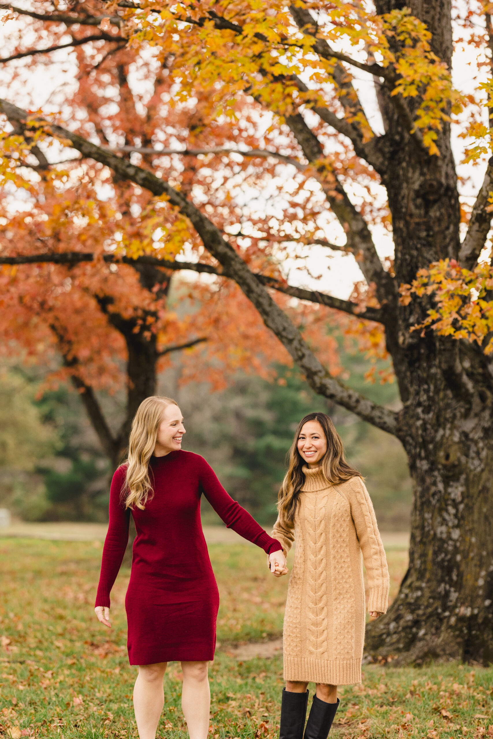 two women holding hands taking fall engagement photos in kansas city 