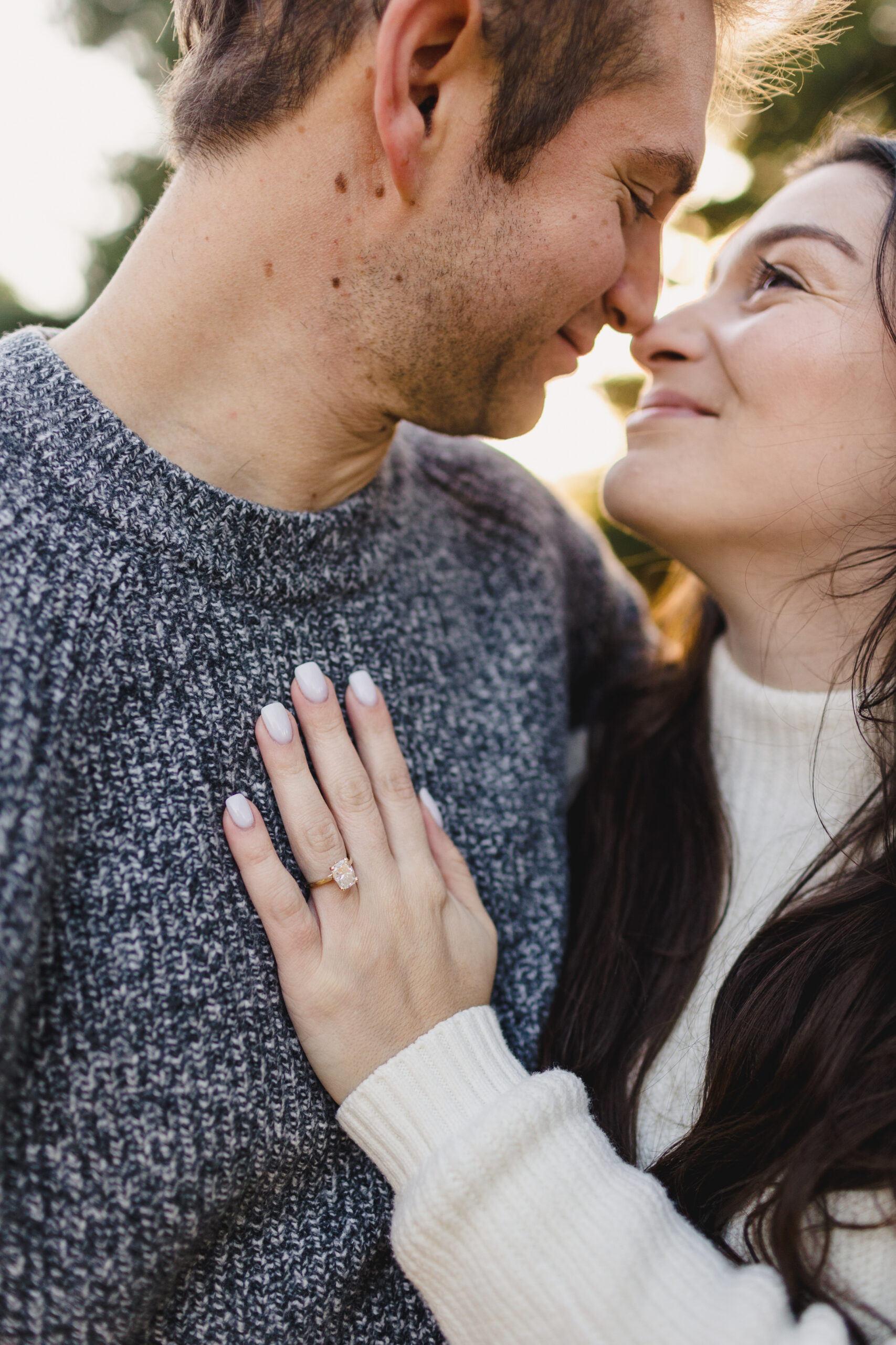 a woman showing off her wedding ring and smiling at her partner during golden hour 