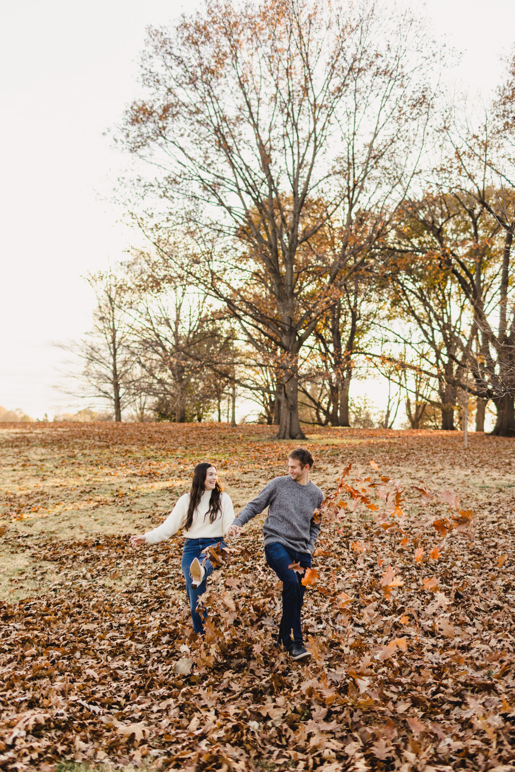 a couple playing in the fall leaves during their kansas city fall engagement session 