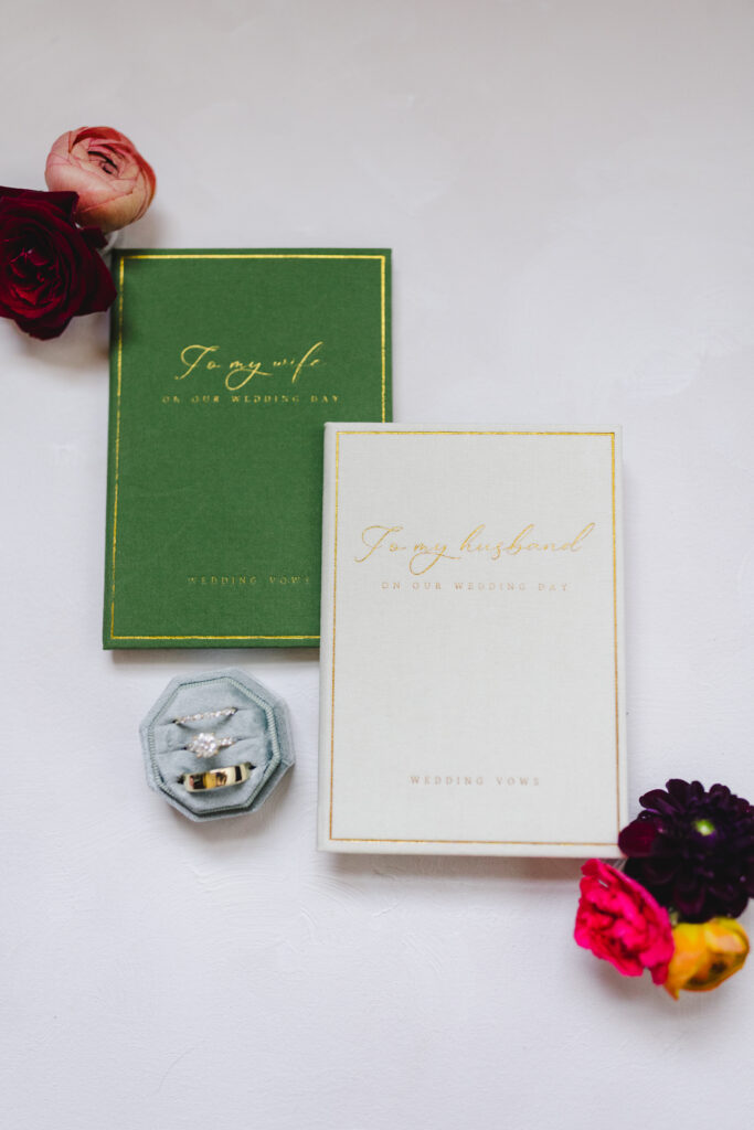 a wedding detail flatly with wedding invitations, flowers, and a ring box with rings 