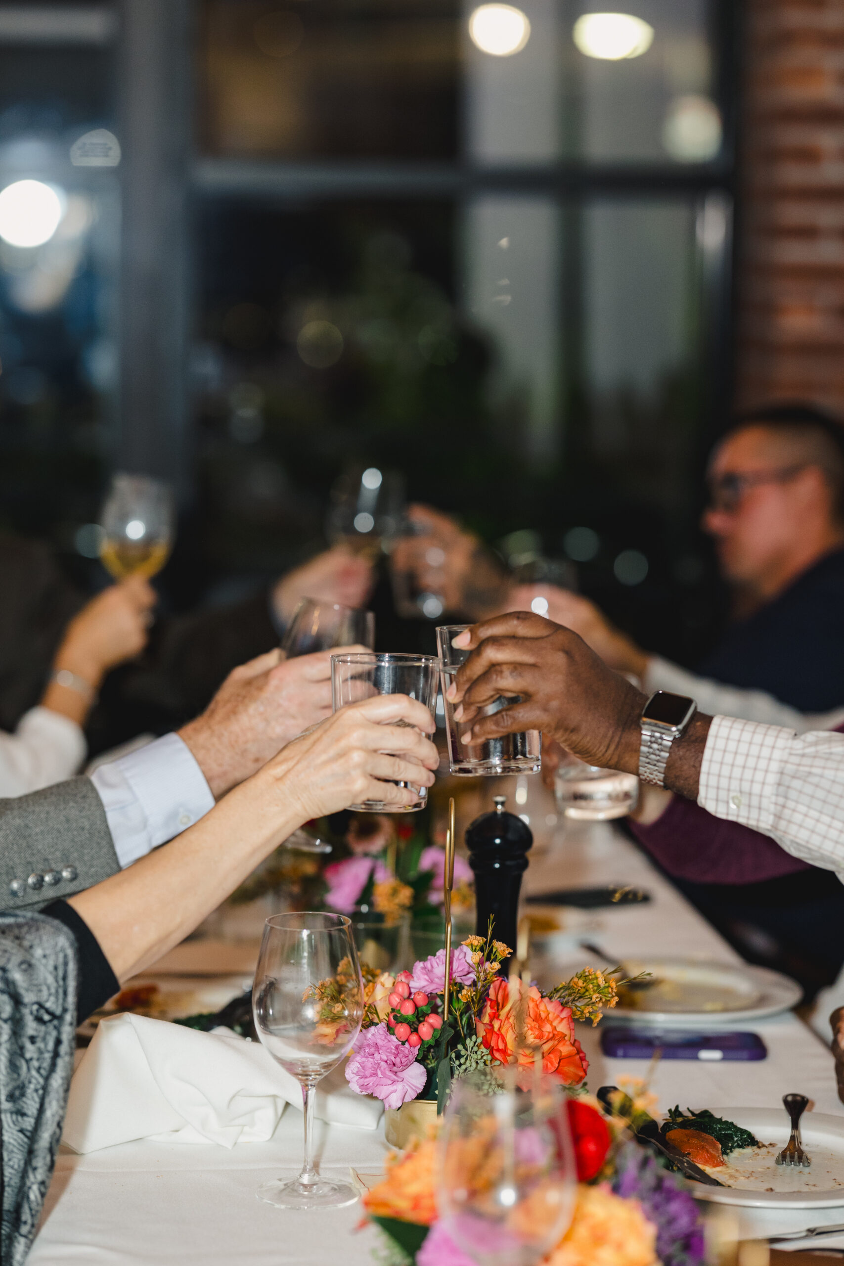 guests cheering with glasses at a wedding rehearsal dinner 