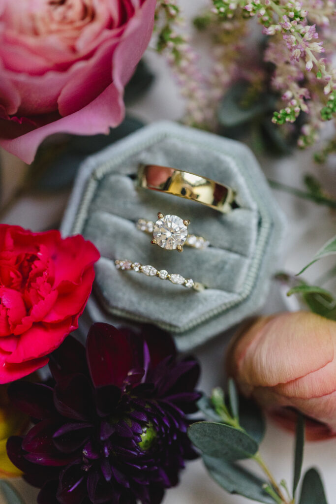 a wedding detail flat lay with flowers and a ring box 