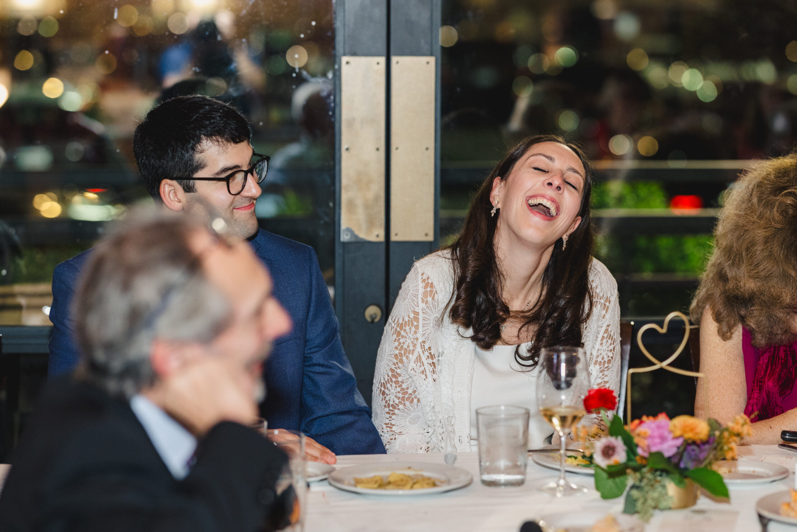 a couple at their rehearsal dinner laughing with each other 