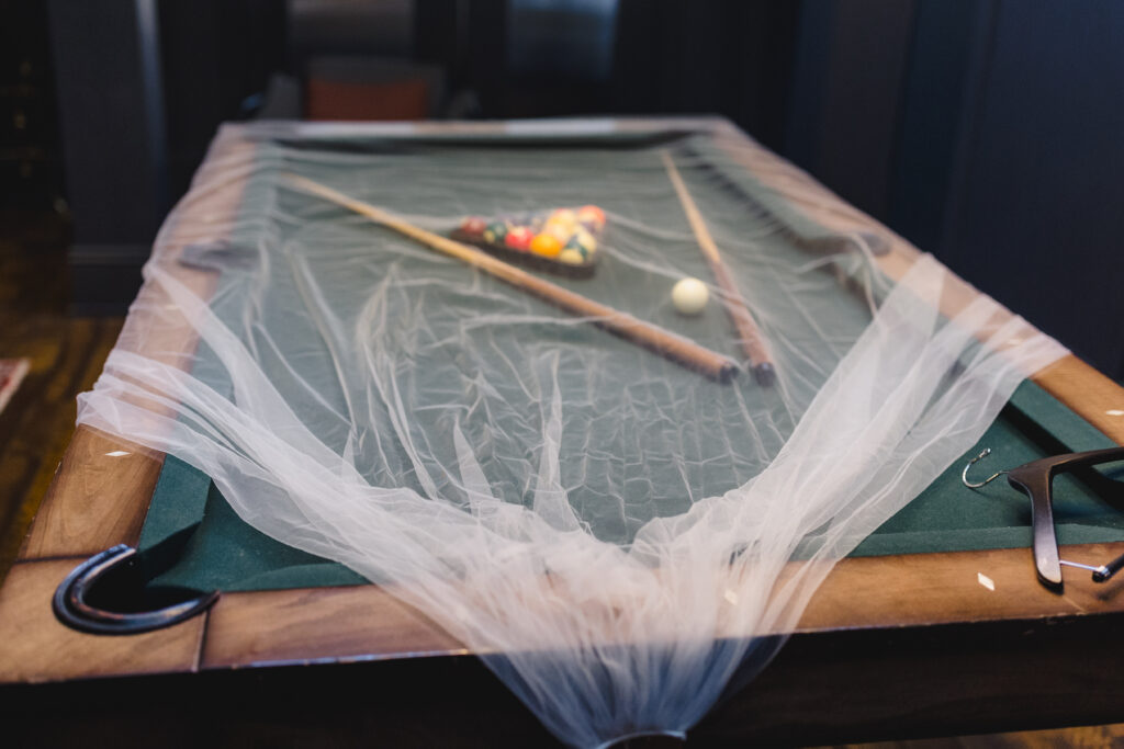 a pool table in the crossroads hotel covered with a bridal veil 