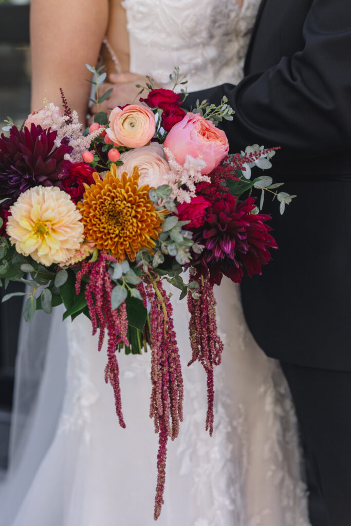 a man and woman embracing the bride is holding a colorful floral bouquet 