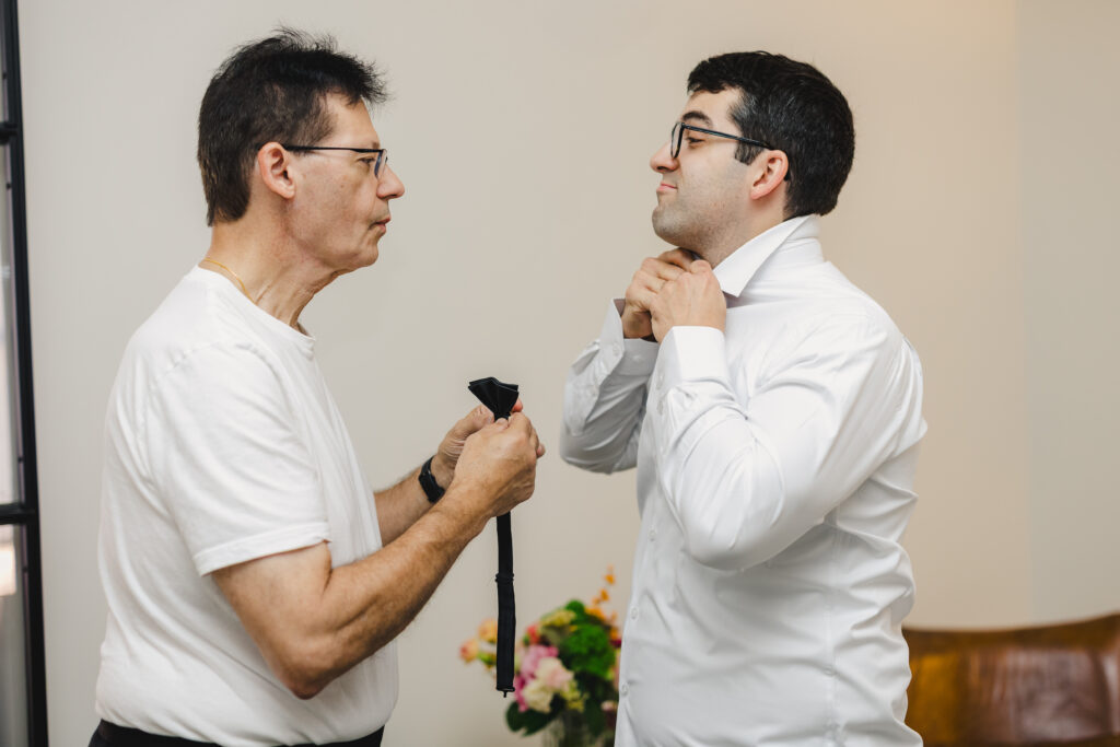 a groom's father helping him get ready for his wedding 