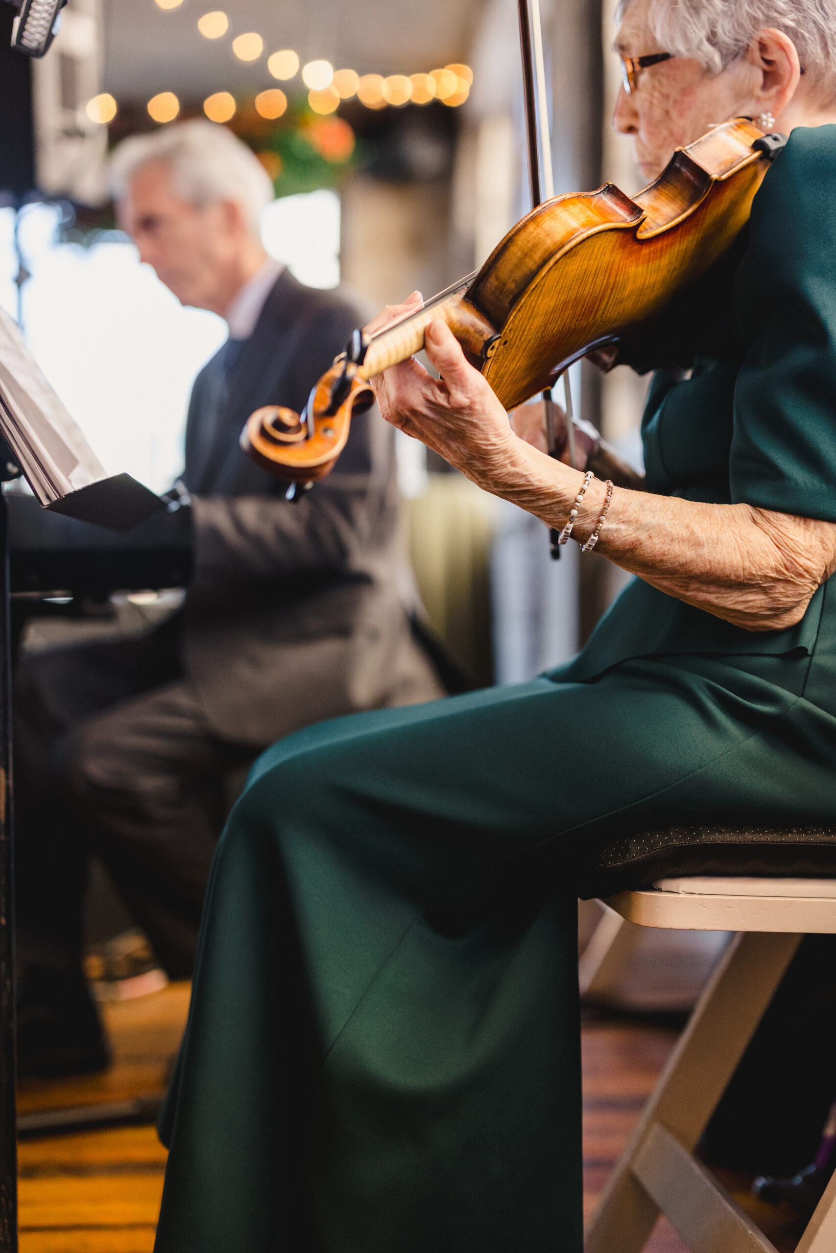 a woman sitting on a chair playing a violin for a wedding ceremony in the bauer 
