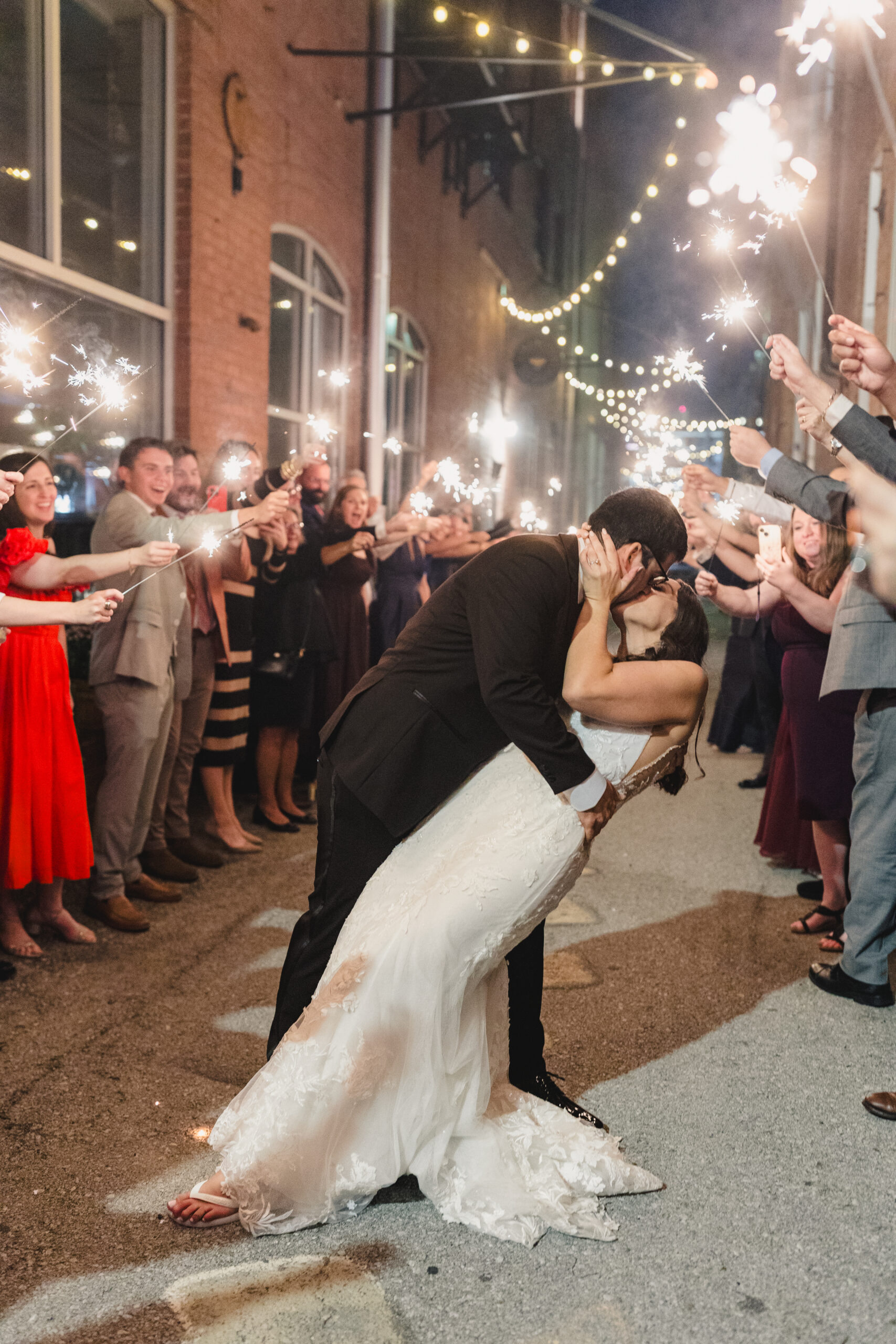 a groom diping his bride and kissing her after their wedding during their sparkler exit 