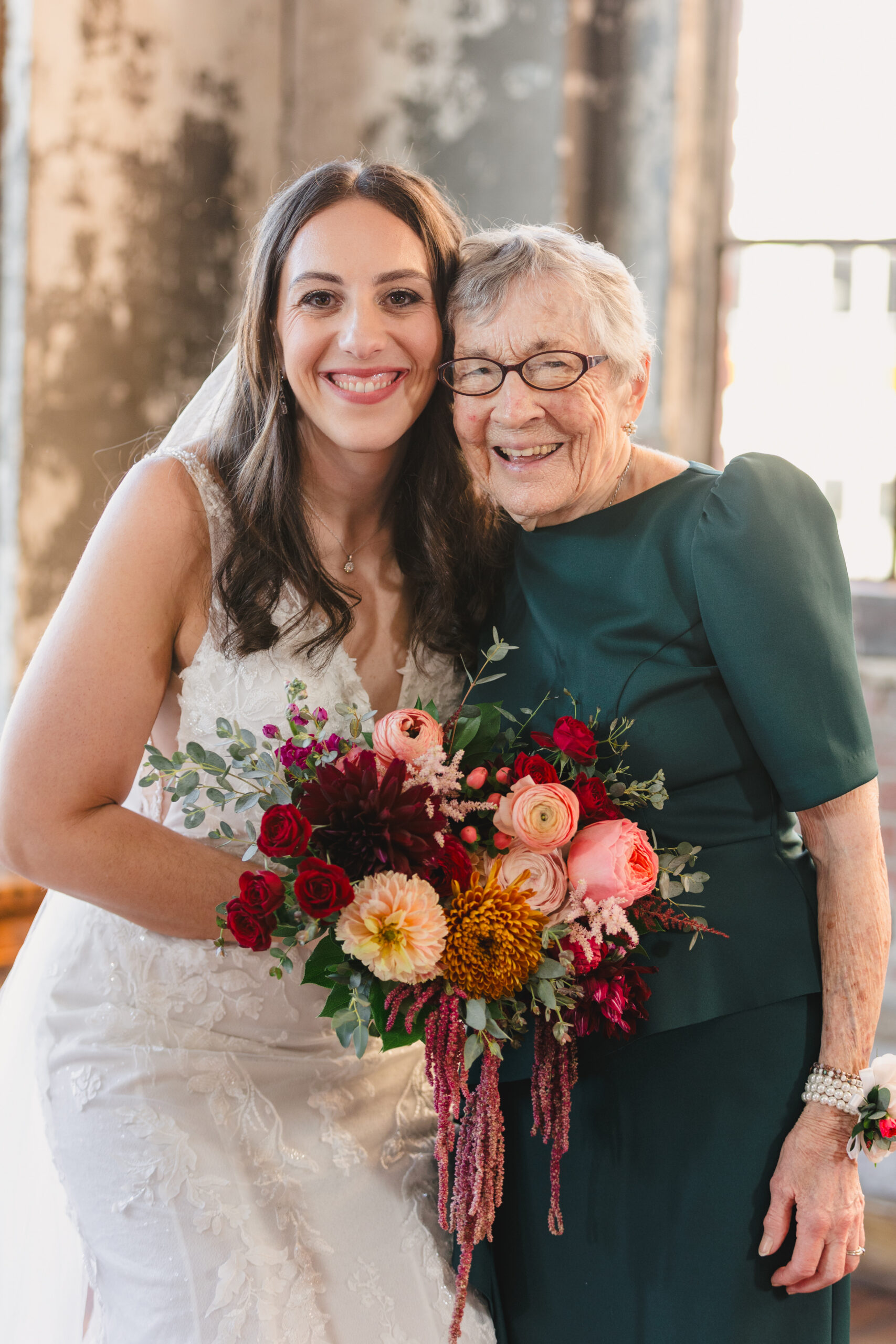a bride holding a bouquet of flowers and smiling with her grandmother 