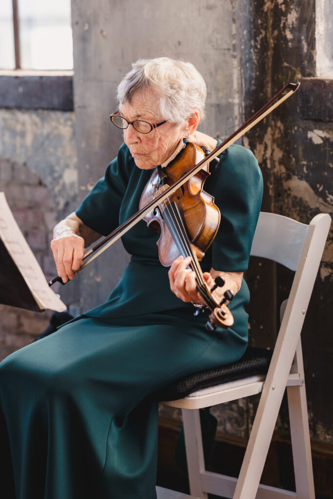 a woman sitting on a chair playing the violin 