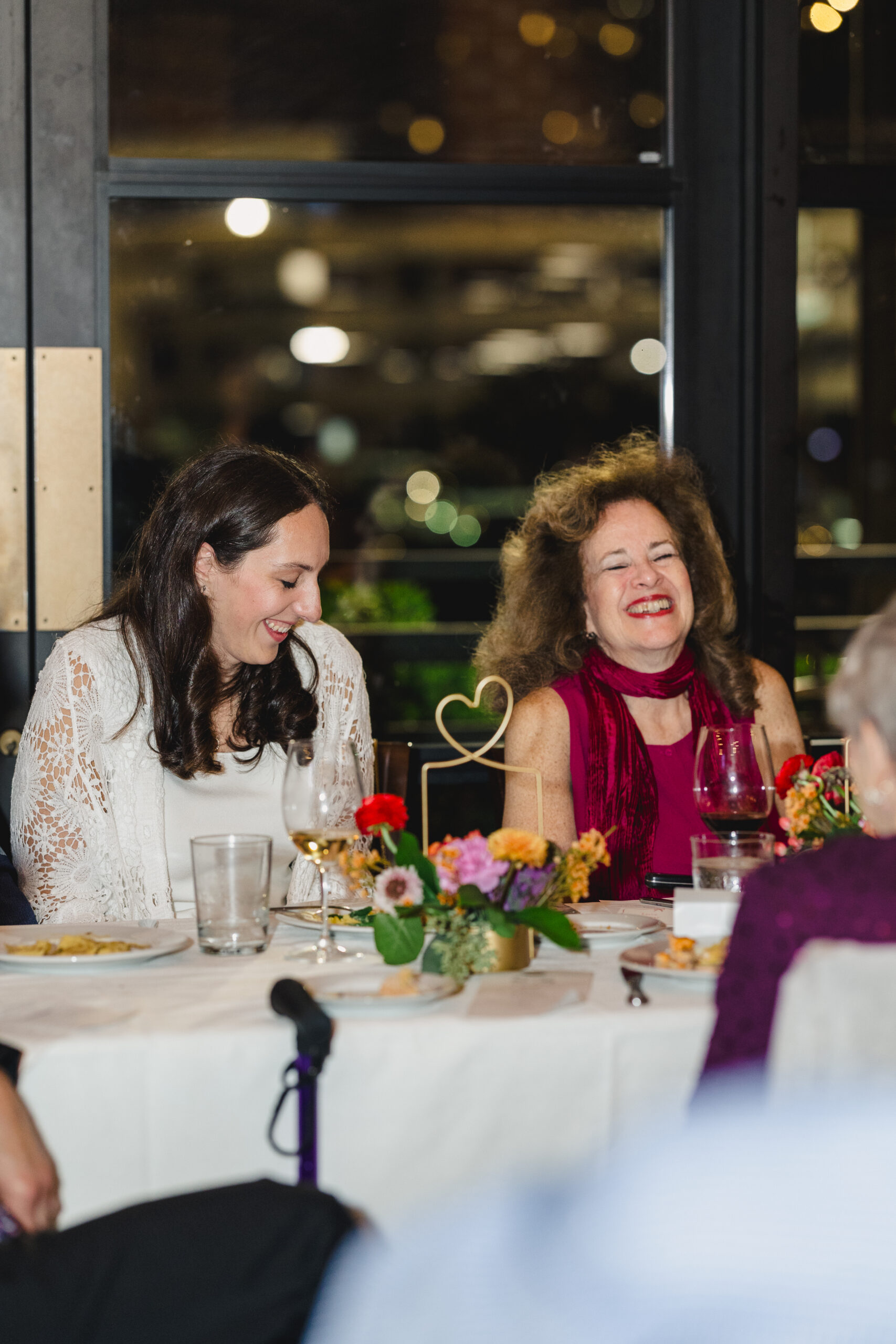 a woman sitting at a table with her her family at her wedding rehearsal dinner 
