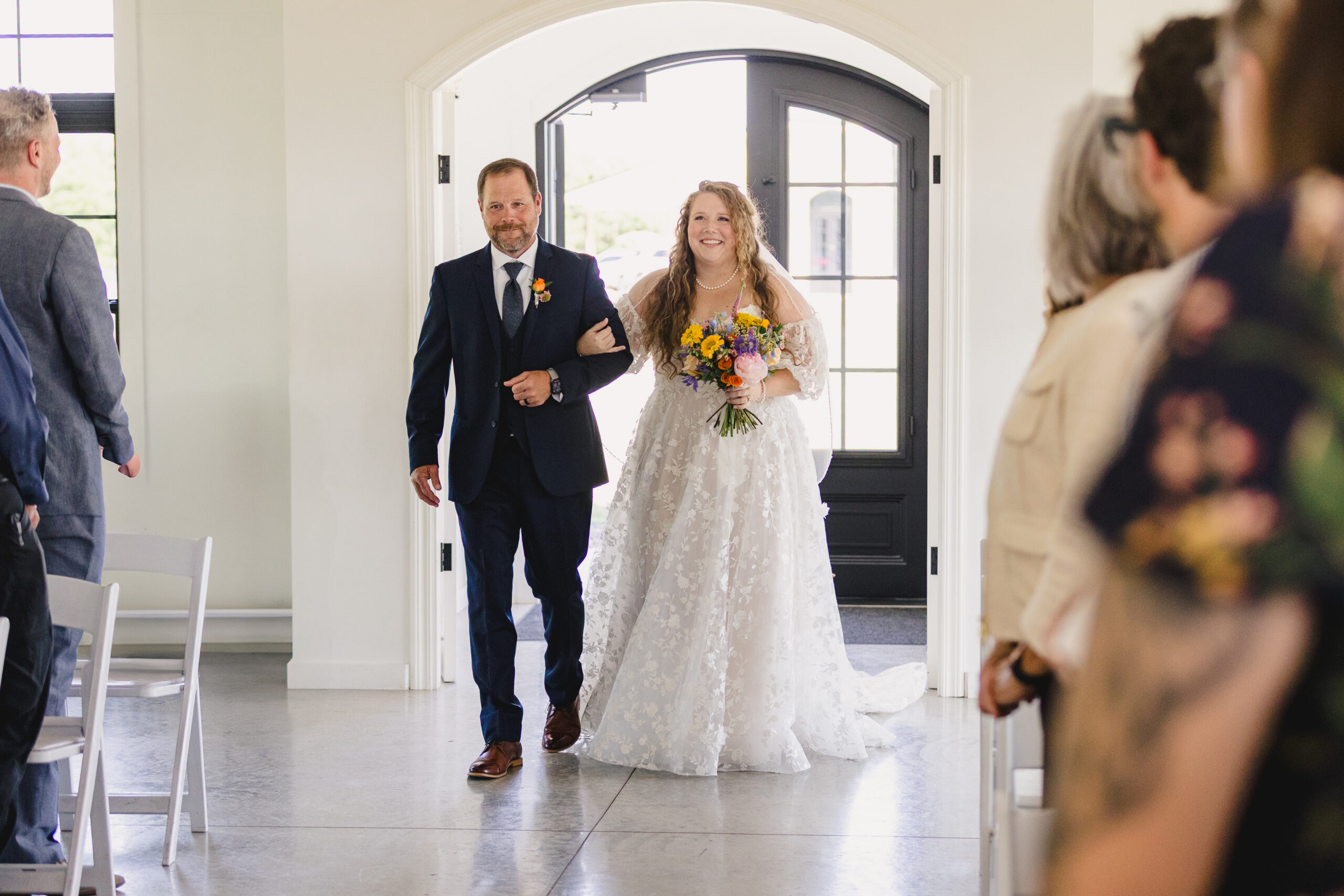 a bride walking down the aisle arm in arm with her father for her wedding ceremony