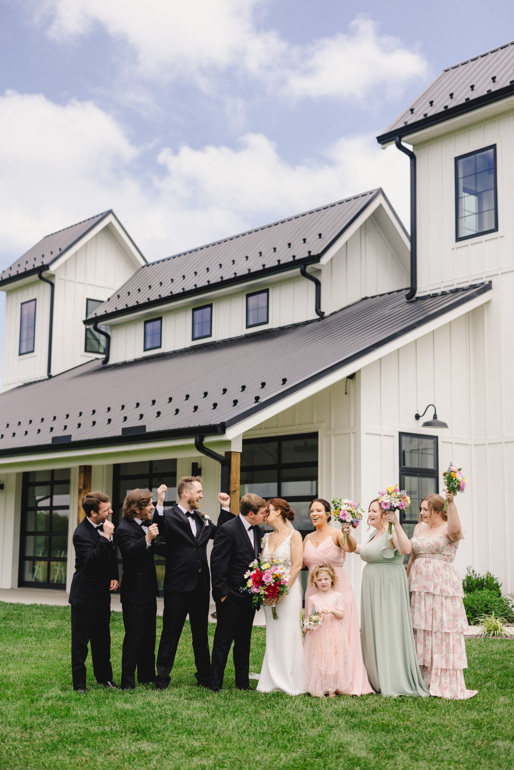a bride and groom kissing in front of the brim in kansas city while their wedding party cheers for them