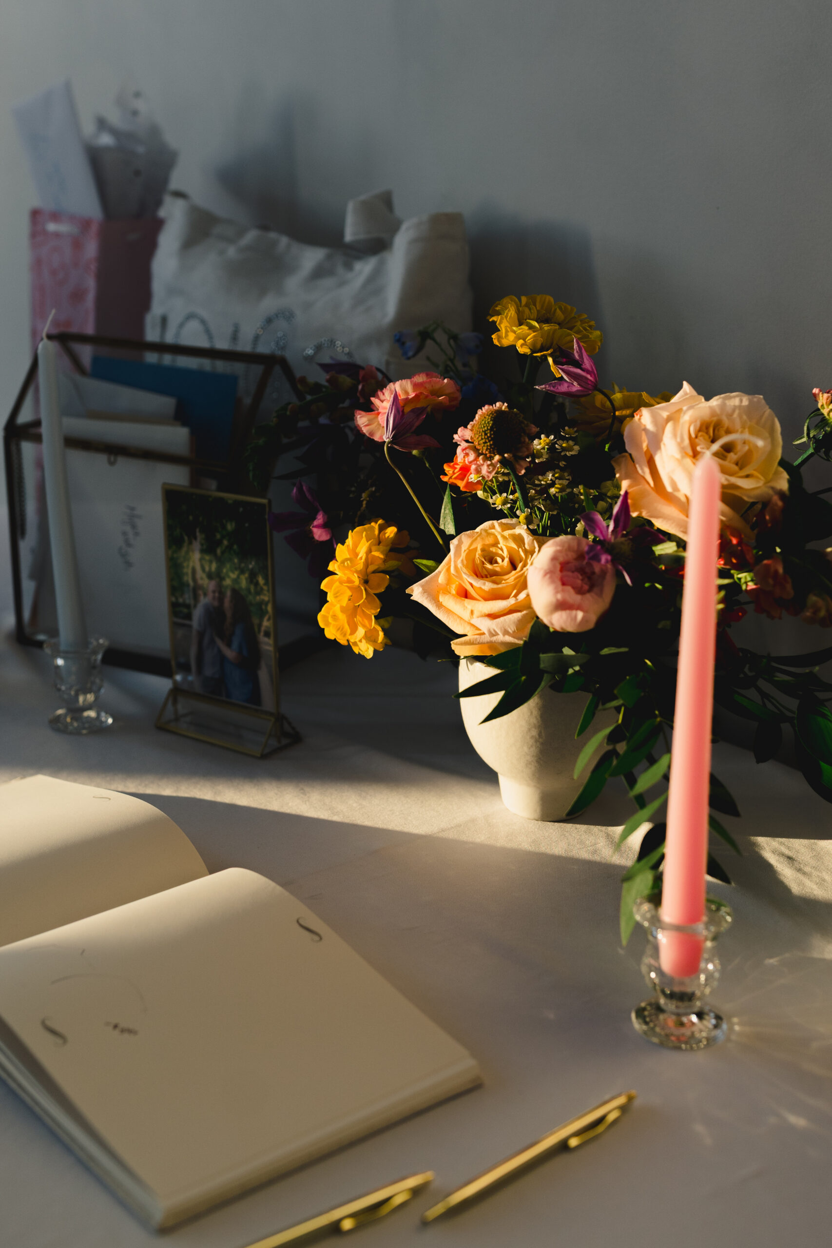 a wedding guest book, candle, and flowersi n a vase on a table