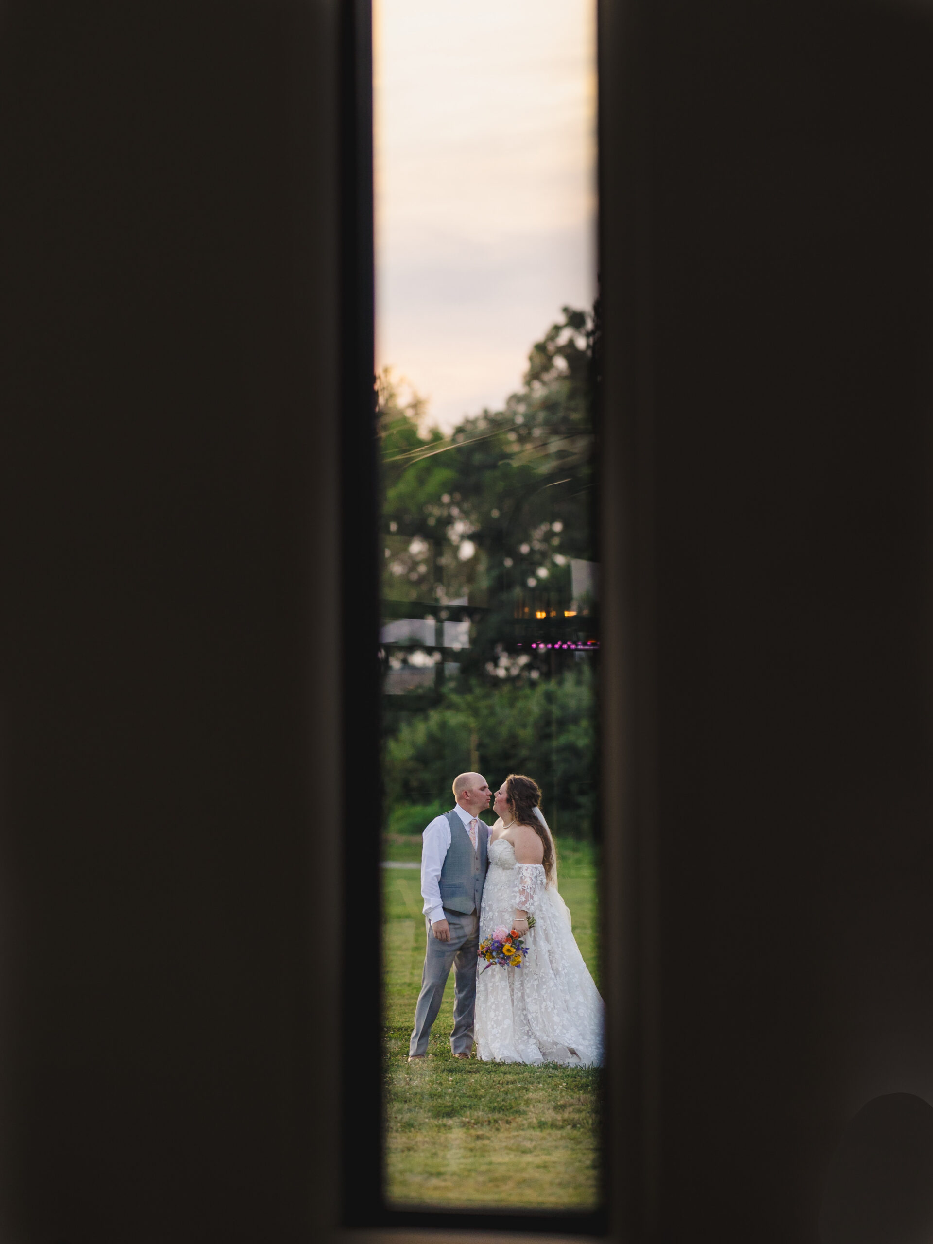 a bride and groom kissing on a lawn
