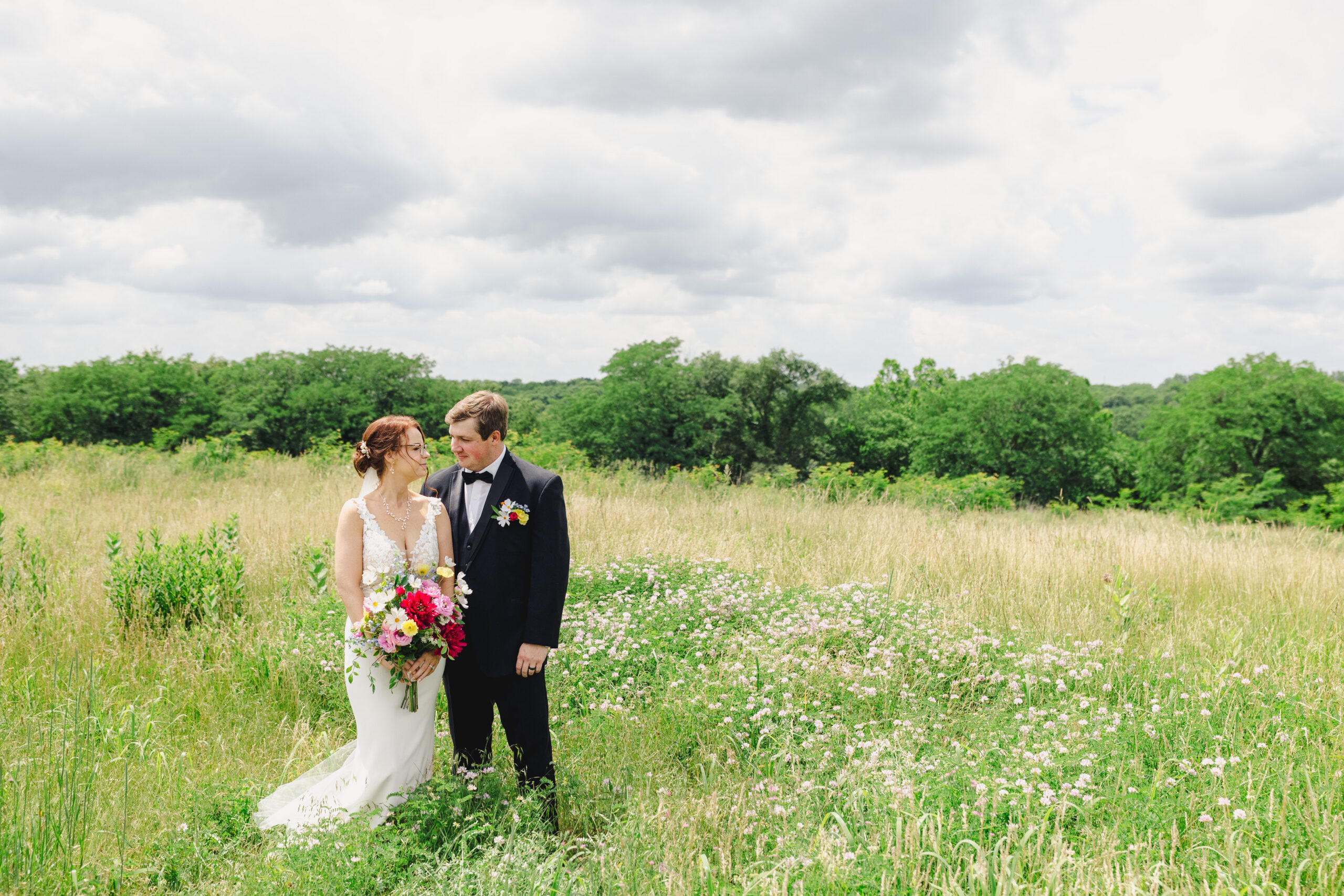 a bride and groom taking wedding portraits in a field