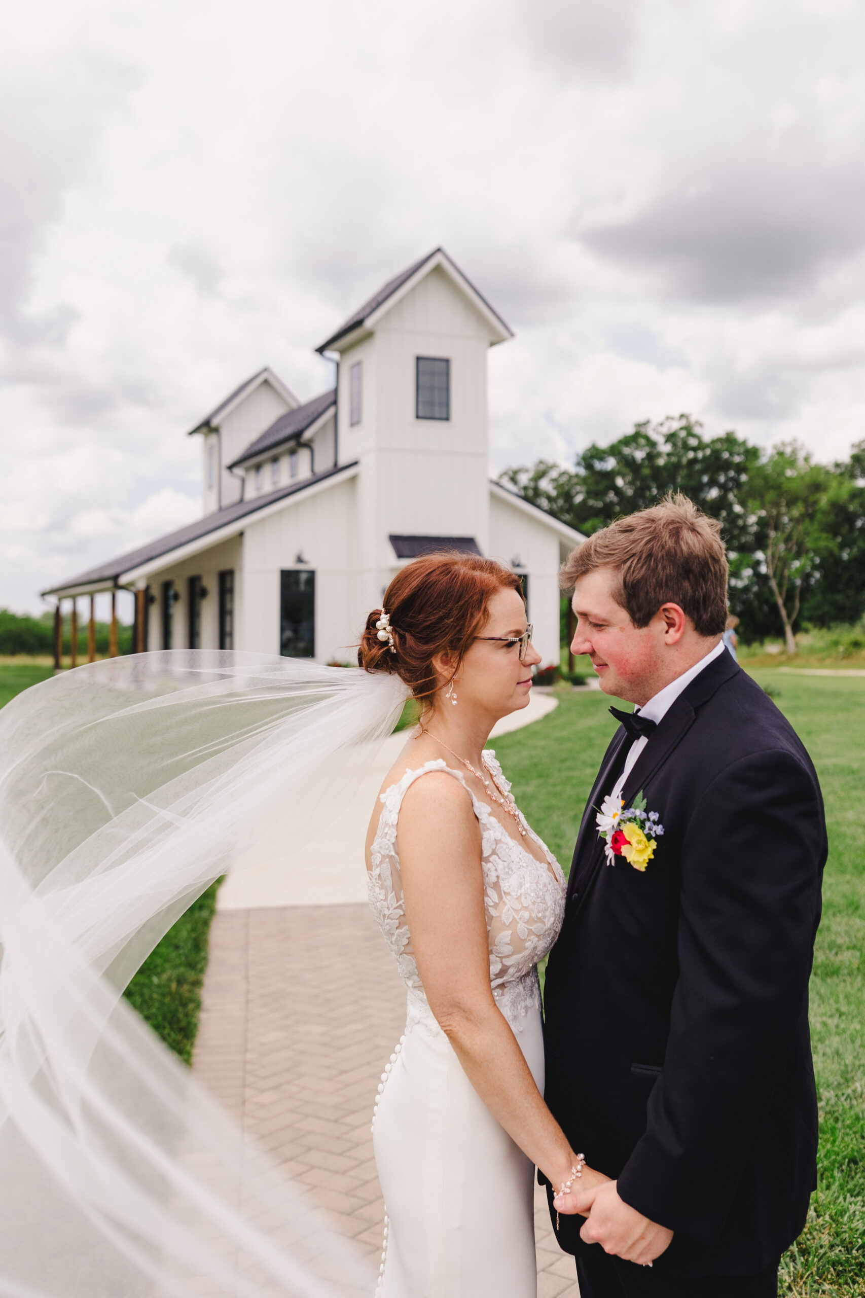 a bride and groom taking wedding portraits as the bride's veil blows behind her in the wind