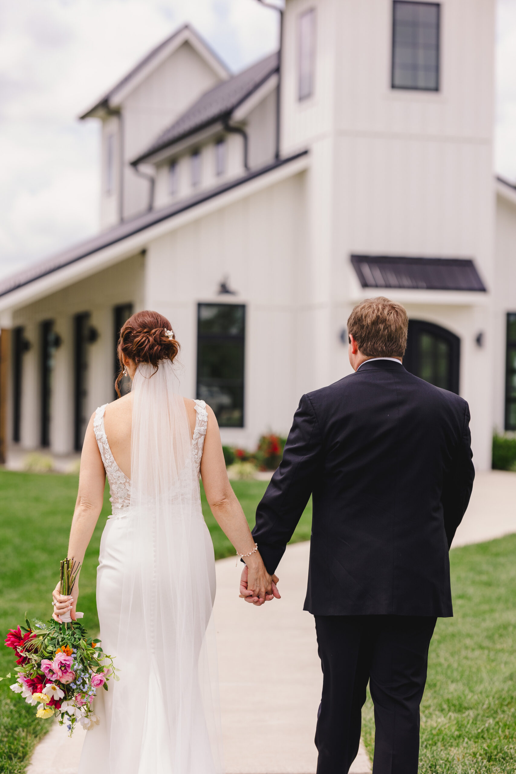 a bride and groom walking together hand in hand