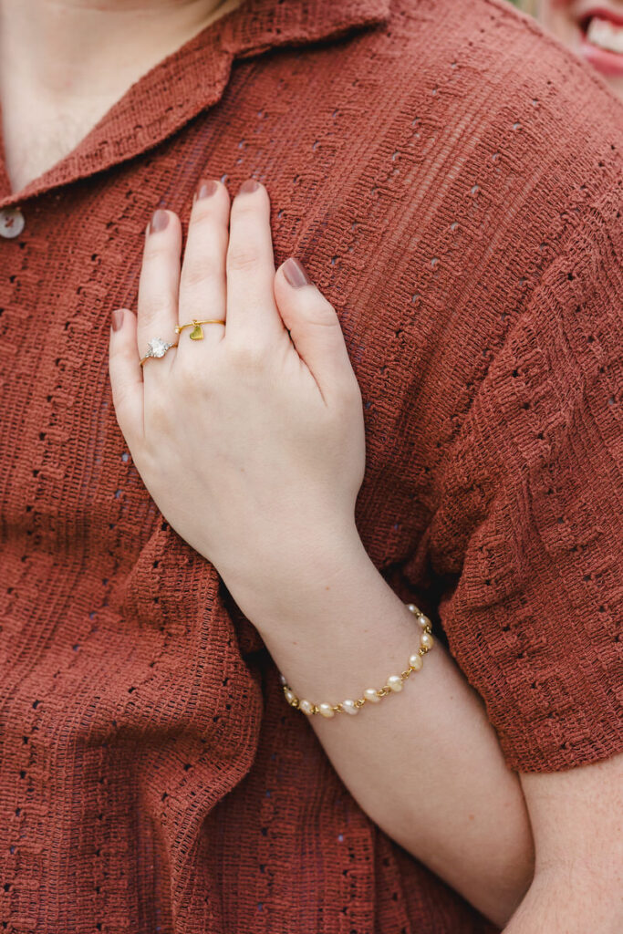 A person hugging their partner from behind showing off an engagement ring