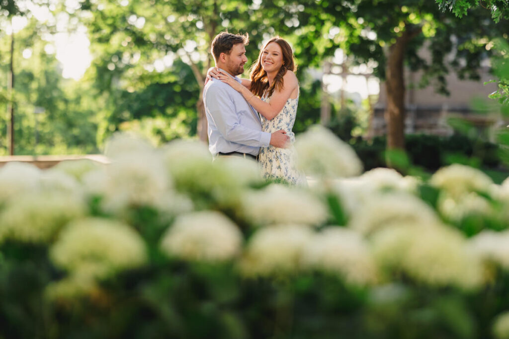 A couple laughing with their arms around each other in a garden