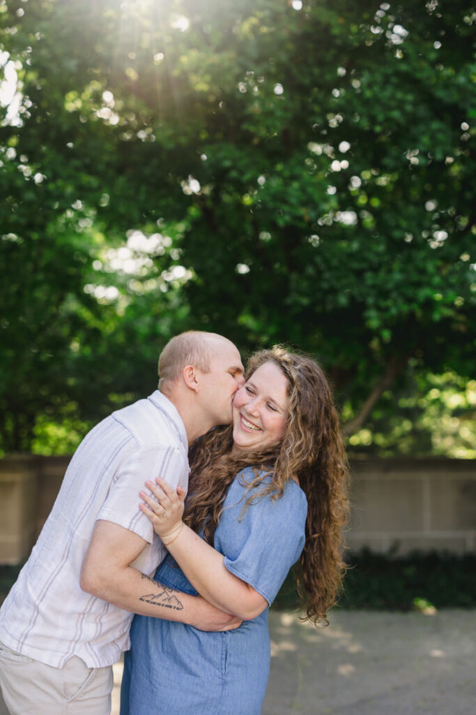 A person laughing as their partner kisses their cheek