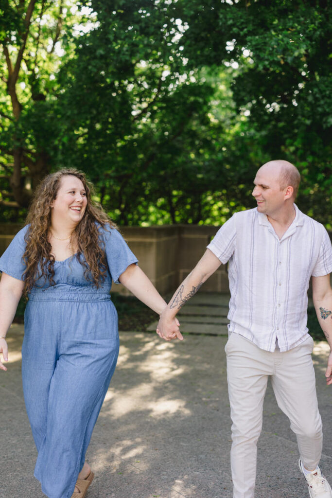 A couple holding hands and laughing as they walk in a park