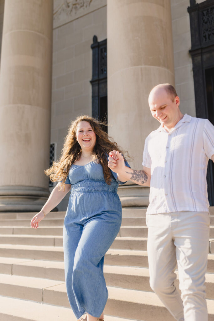 A couple holding hands and running down an outdoor staircase
