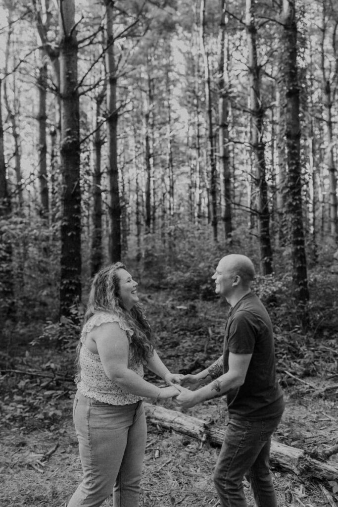 A couple holding hands and laughing in the woods