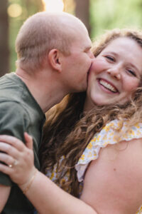 A person laughing as their partner kisses their cheek 
