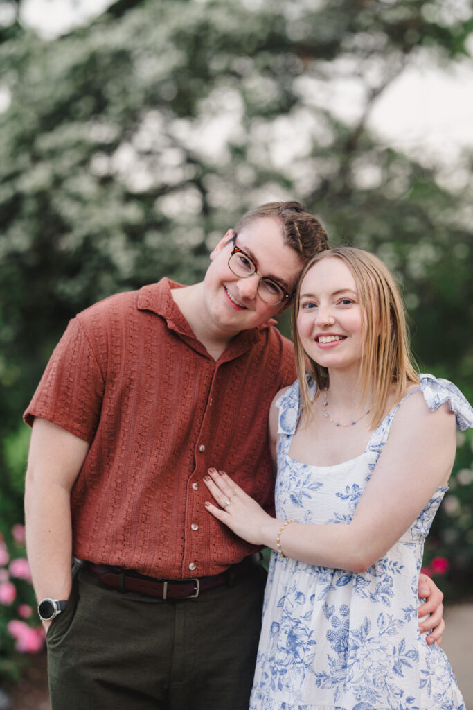 A couple smiling with their arms around each other as they lean into each other