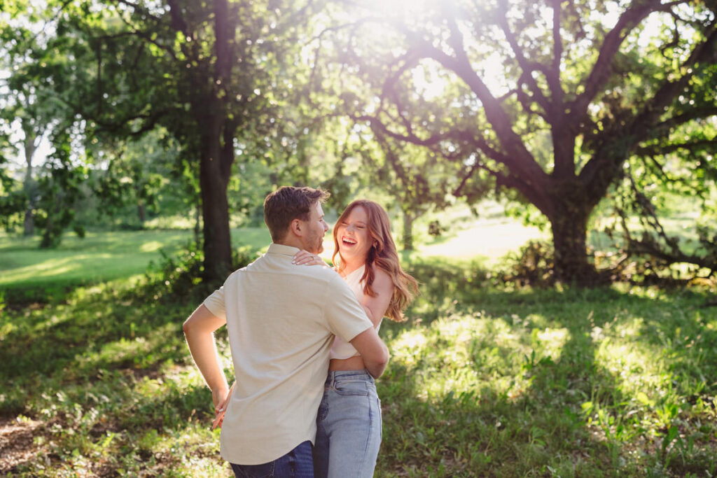A couple laughing as they hug each other in a park