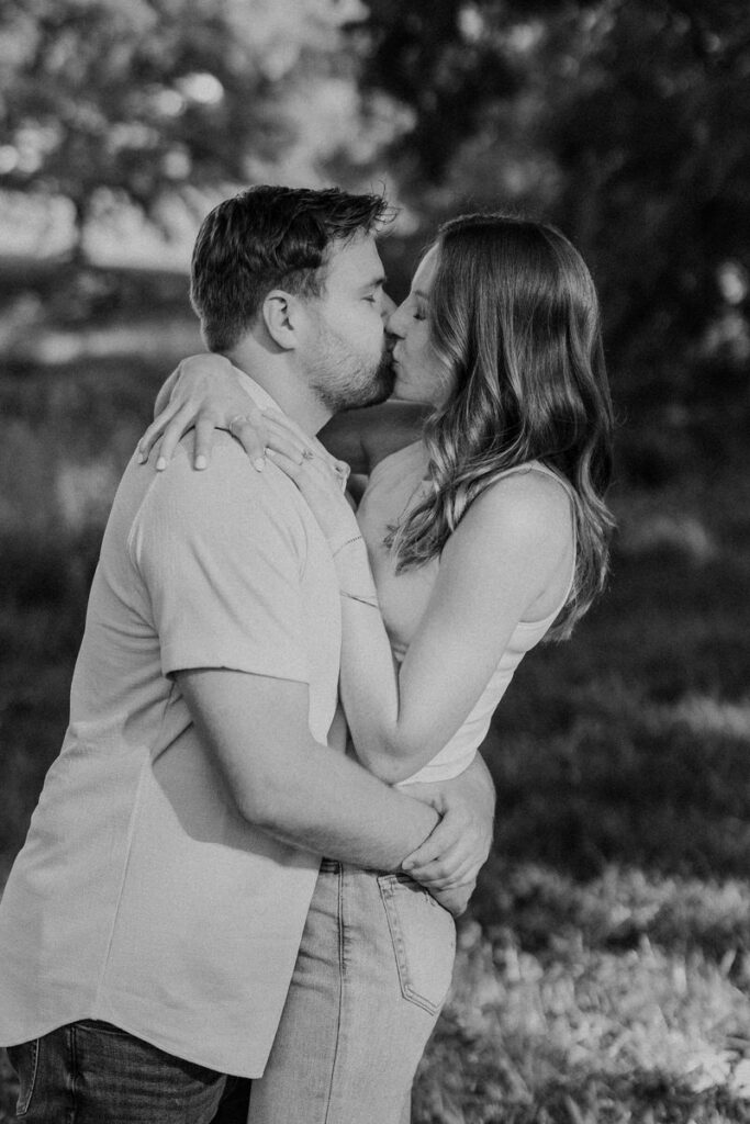A couple kissing in the park with their arms around each other
