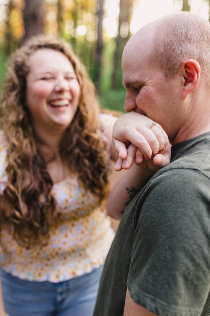 A person laughing as they partner kisses their hand