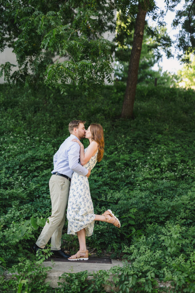 A couple kissing while one kicks one of their legs up behind them
