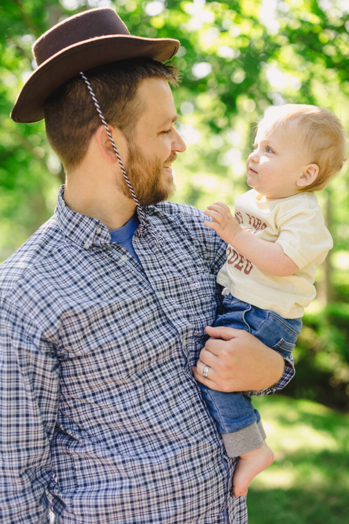 A parent holding their toddler as they wear the toddler's cowboy hat 