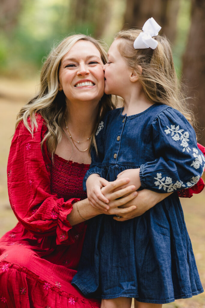 A young child kissing their parent's cheek as they smile 