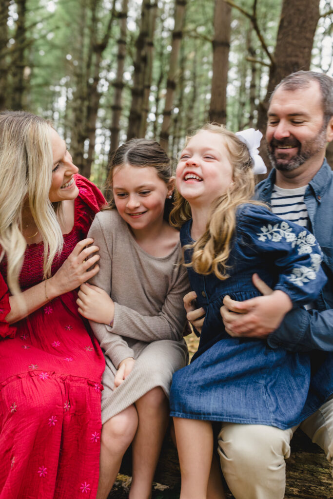 Parents sitting on either side of their kids as they tickle them 