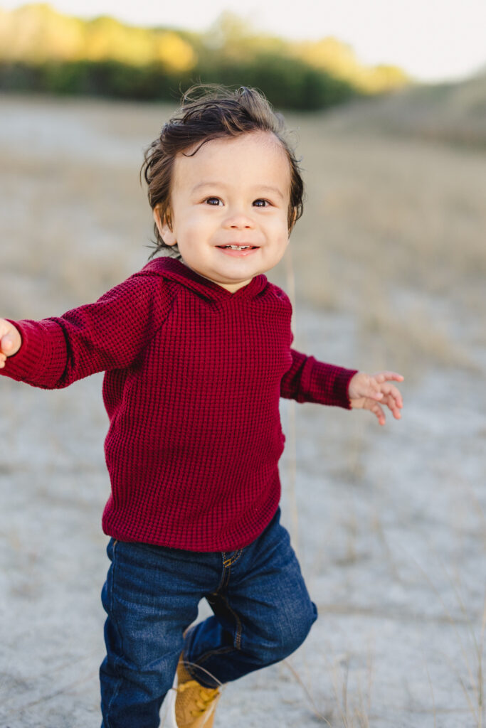 A toddler running on a beach and laughing 