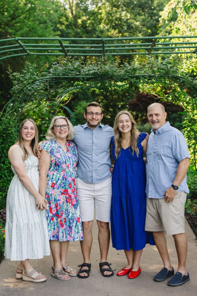 Parents and their grown children standing in a garden as they smile together 