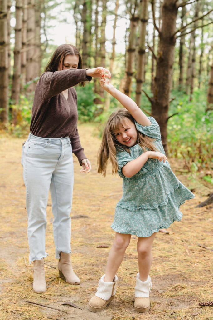 A parent dancing with their child in a wooded area 