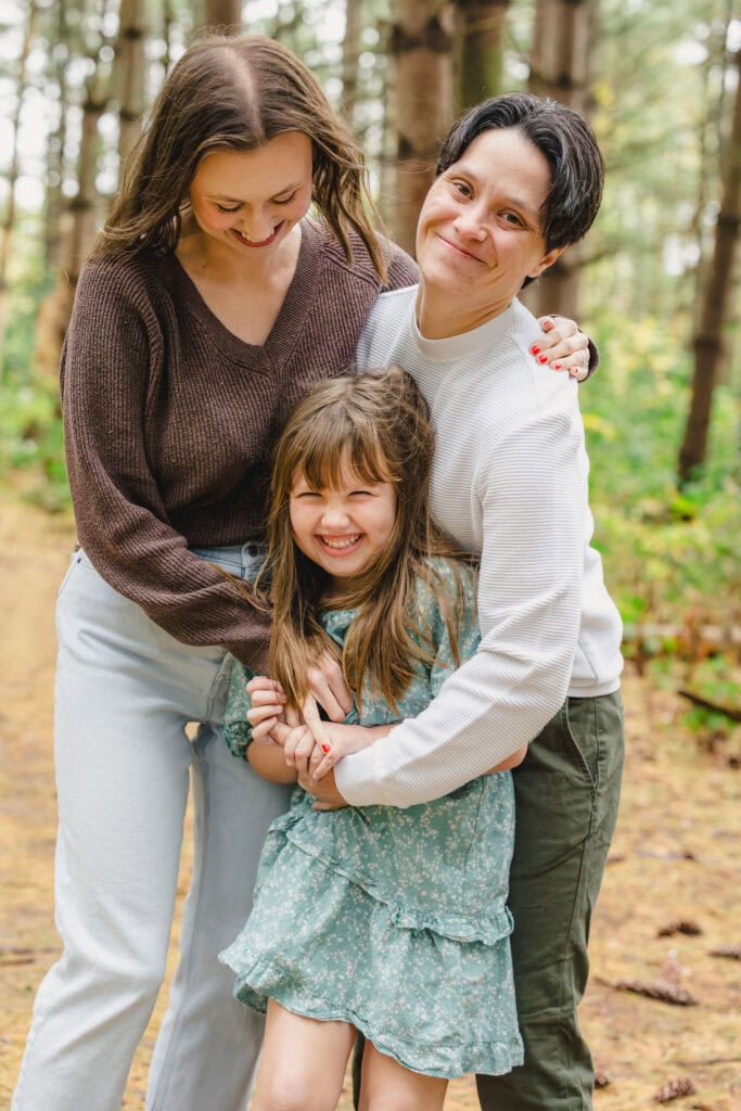 Parents laughing as they tickle their child in front of them 