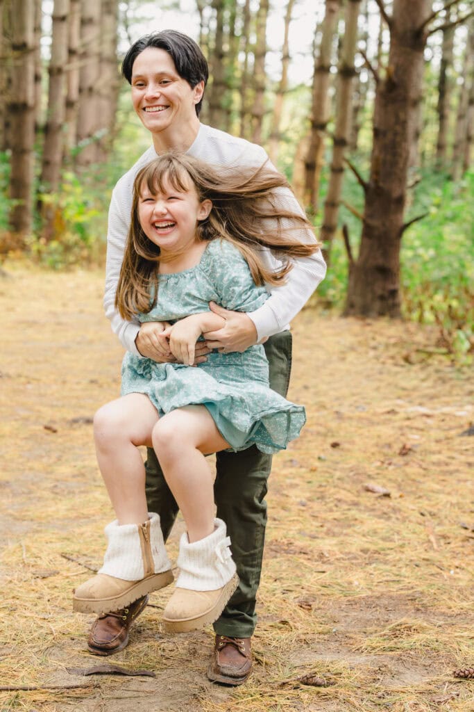 A parent holding their child up as they both laugh 