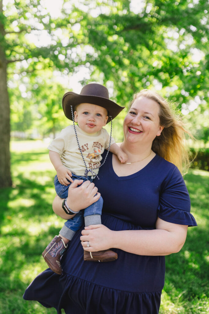 A parent holding their child on their hip while smiling 