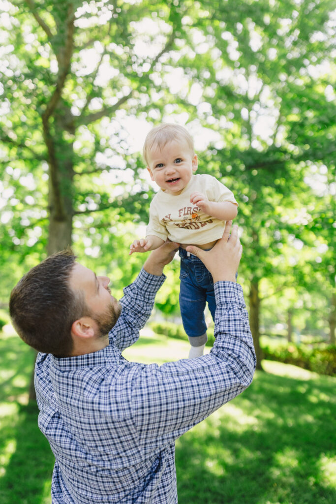 A parent throwing their toddler up in the air as they laugh 
